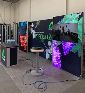 RENTAL: RE-2138 Inline Design with (3) Single-Sided Lightboxes, (2) Large Monitor Mounts, 60” Monitors, RE-1567 Backlit Reception Counter, (2) RE-711 Charging Station Tables, SEG Backlit Fabric Graphics, and Vinyl Applied Graphics -- View 2